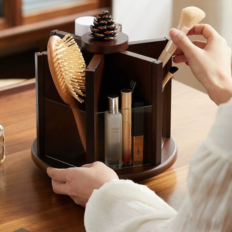 Rotating wooden makeup organizer holding cosmetics, makeup brushes, perfume, and a hairbrush on a vanity