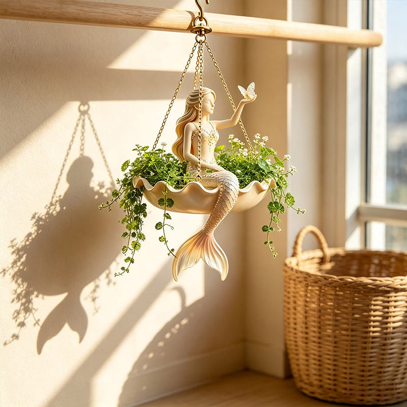 Planter hanging on a wooden dowel with greenery growing inside and a mermaid sitting in the middle.