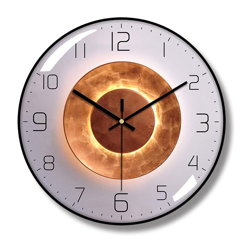Round wall clock with a black frame, pale gray face, black hands and numerals, and concentric copper-colored circle artwork.