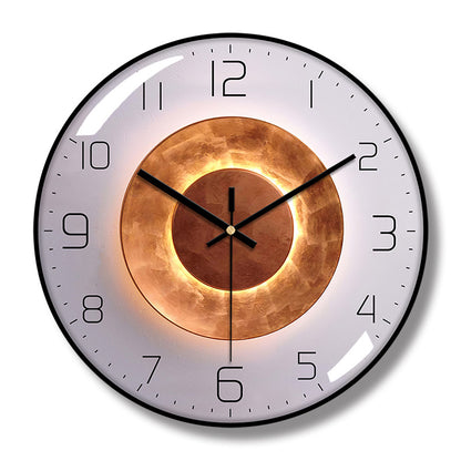 Round wall clock with a black frame, pale gray face, black hands and numerals, and concentric copper-colored circle artwork.