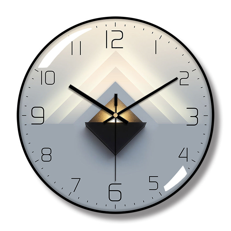 Round wall clock with a black frame, black hands and numerals, and layered cream, gray, and black triangular artwork.
