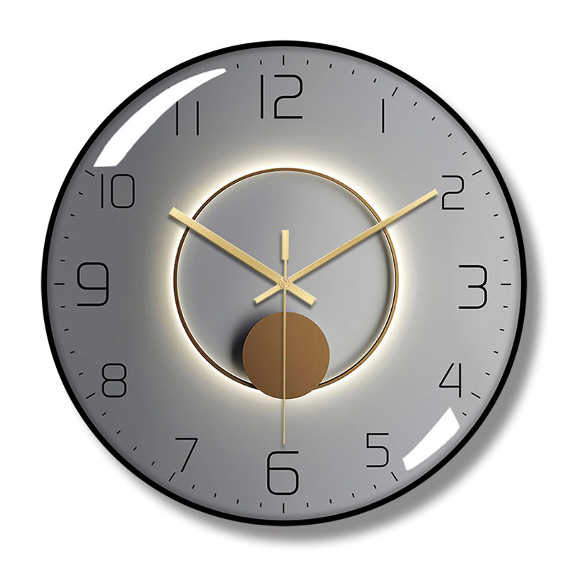 Round wall clock with a black frame, gray face, black numerals, gold-colored hands, and a central ring and circle design.