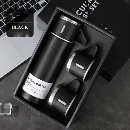Black vacuum flask with a matching handled cup on top and two additional cups arranged in a black gift box.