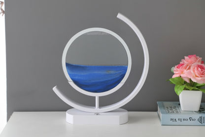 Front view of a white table lamp with blue sand layered inside a circular display and a curved outer light.