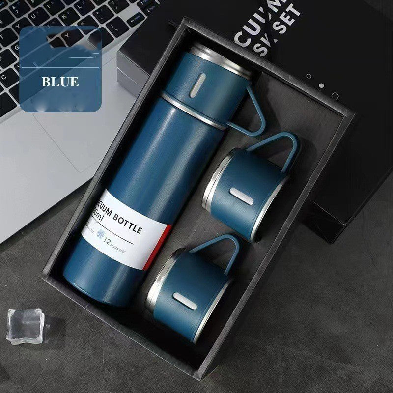 Blue vacuum flask with a matching handled cup on top and two additional cups arranged in a black gift box.