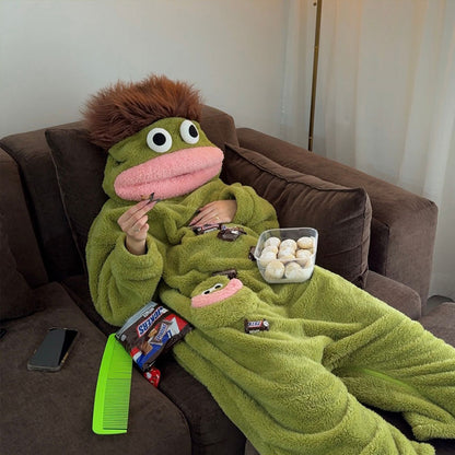 Person reading on the floor in green plush fish onesie pajamas inside a cozy living room.