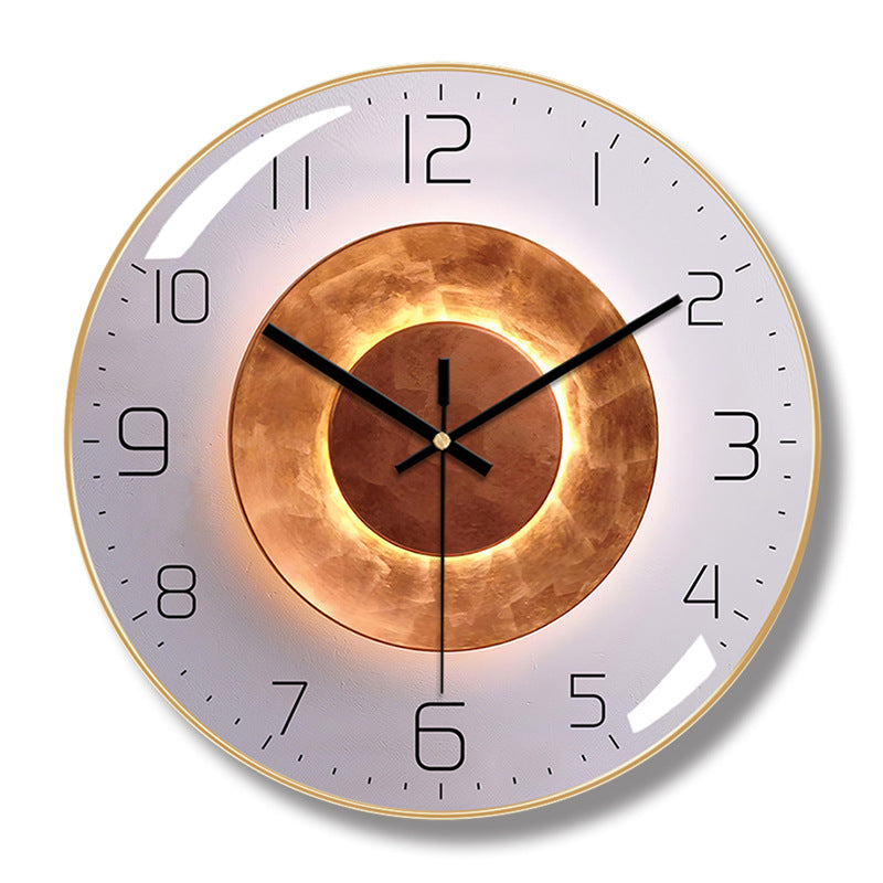 Round wall clock with a gold-colored frame, pale gray face, black hands and numerals, and concentric copper-colored circle artwork.