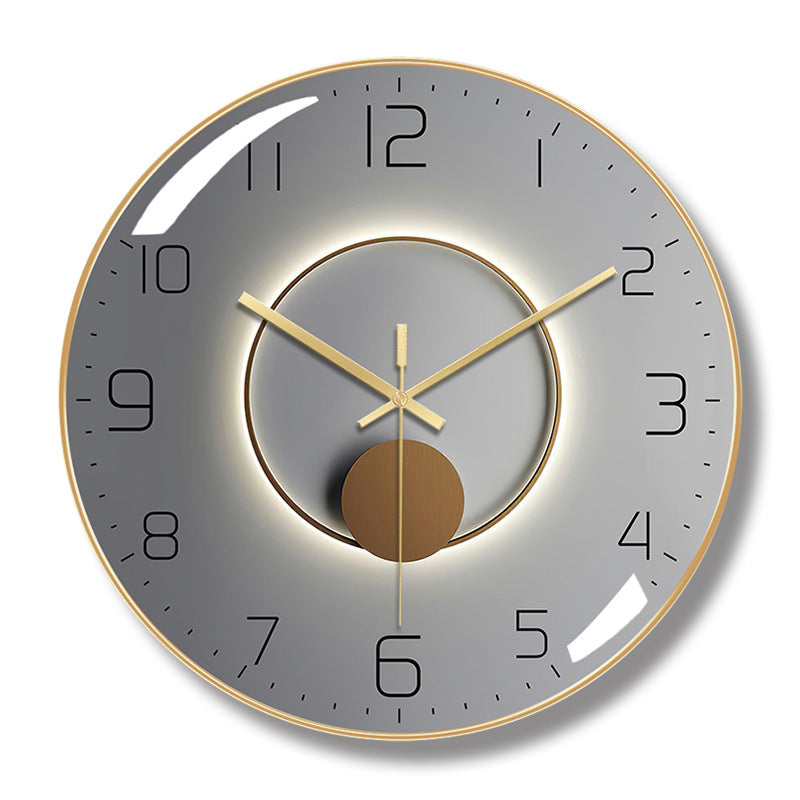 Round wall clock with a gold-colored frame, gray face, black numerals, and a central ring and circle design.