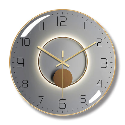 Round wall clock with a gold-colored frame, gray face, black numerals, and a central ring and circle design.
