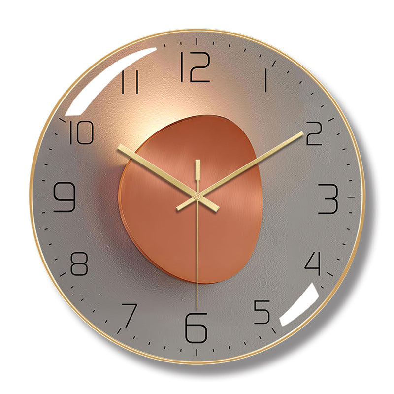 Round wall clock with a gold-colored frame, gray face, black numerals, and gold-colored hands over an orange oval design.