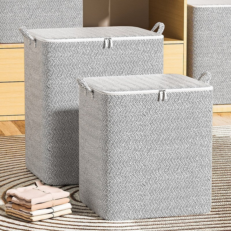Gray herringbone fabric storage bins with lids and handles arranged beside folded clothing in a closet.
