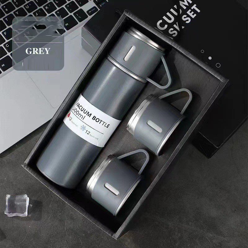 Gray vacuum flask with a matching handled cup on top and two additional cups arranged in a black gift box.
