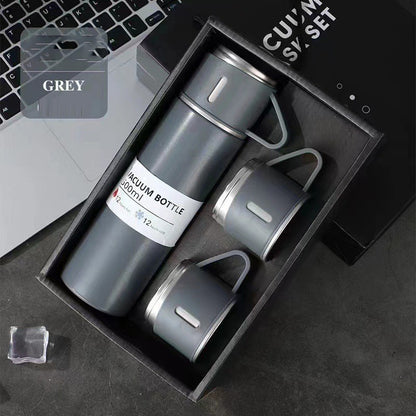 Gray vacuum flask with a matching handled cup on top and two additional cups arranged in a black gift box.