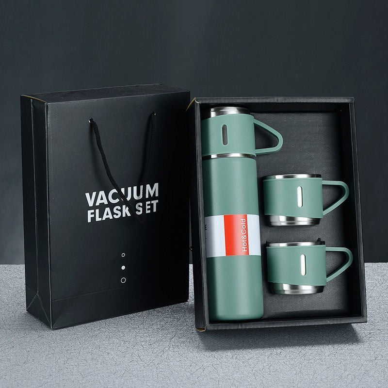 Green vacuum flask and three matching handled cups displayed in an open gift box beside a black gift bag.