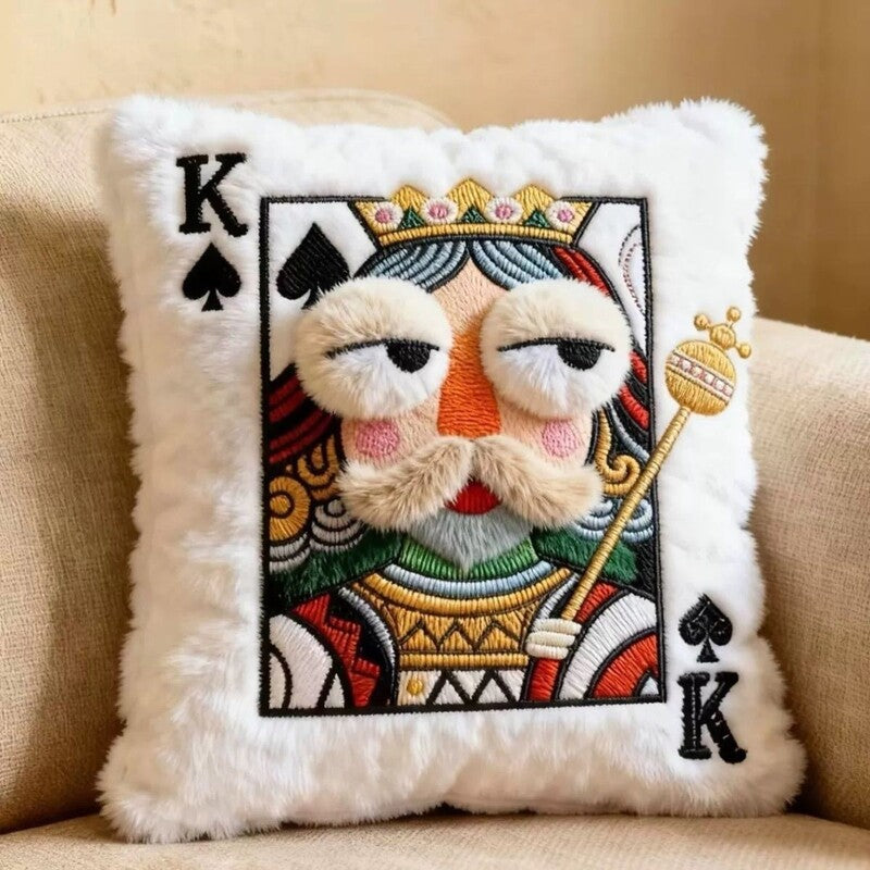 Embroidered King playing card throw pillow with plush facial details displayed on a beige sofa.