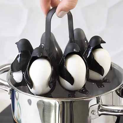 Hand lifting a black penguin-shaped egg holder filled with white eggs above a stainless steel cooking pot.