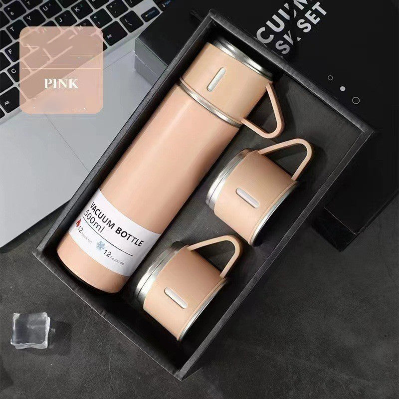 Pink vacuum flask with a matching handled cup on top and two additional cups arranged in a black gift box.