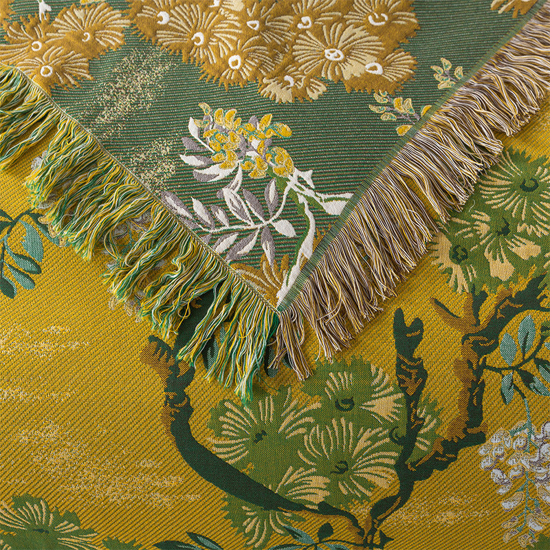Close-up of both sides of the reversible jungle-pattern cotton blanket with decorative fringed edges.
