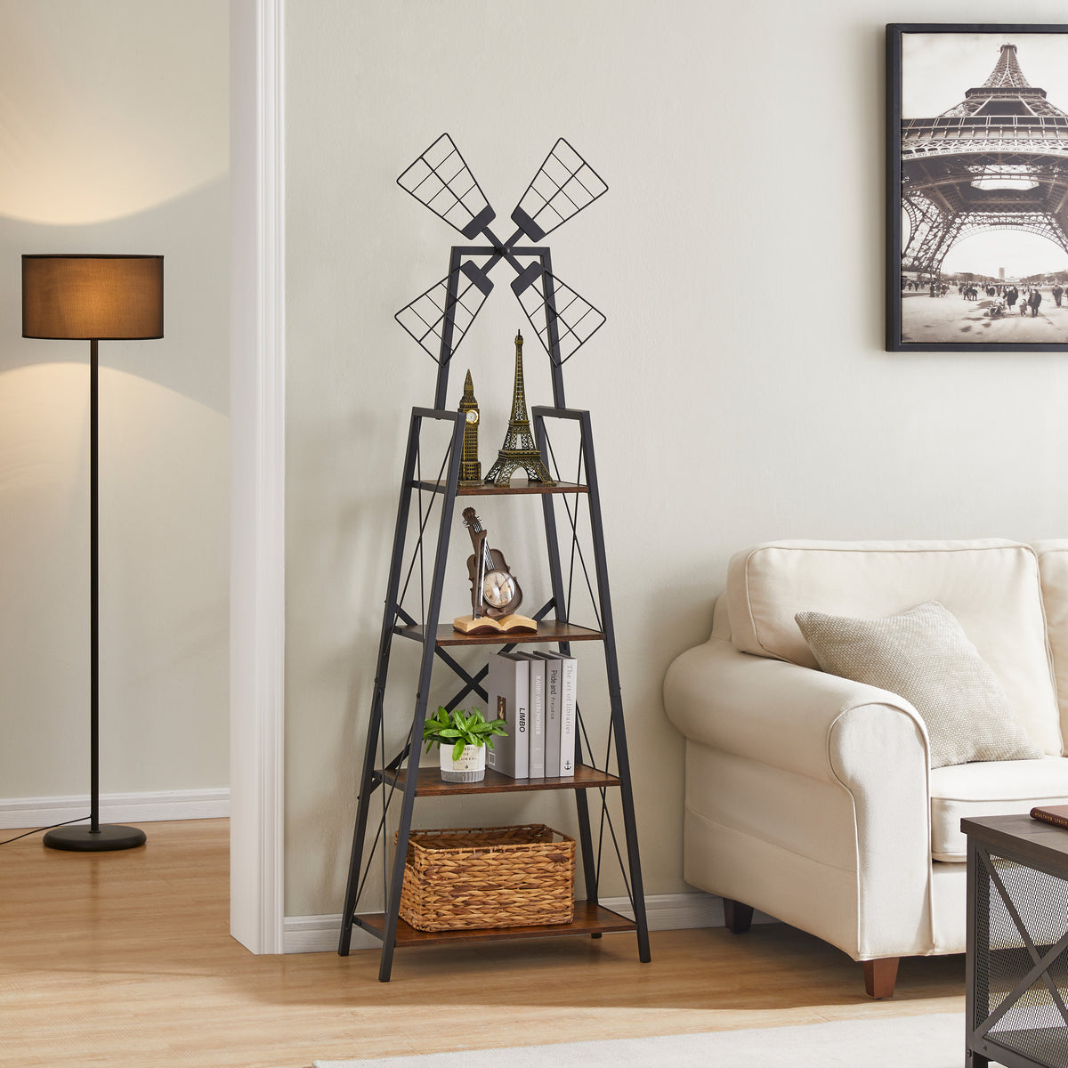 Brown and black windmill bookshelf displaying ornaments, books, a plant, and a woven basket beside a cream sofa.