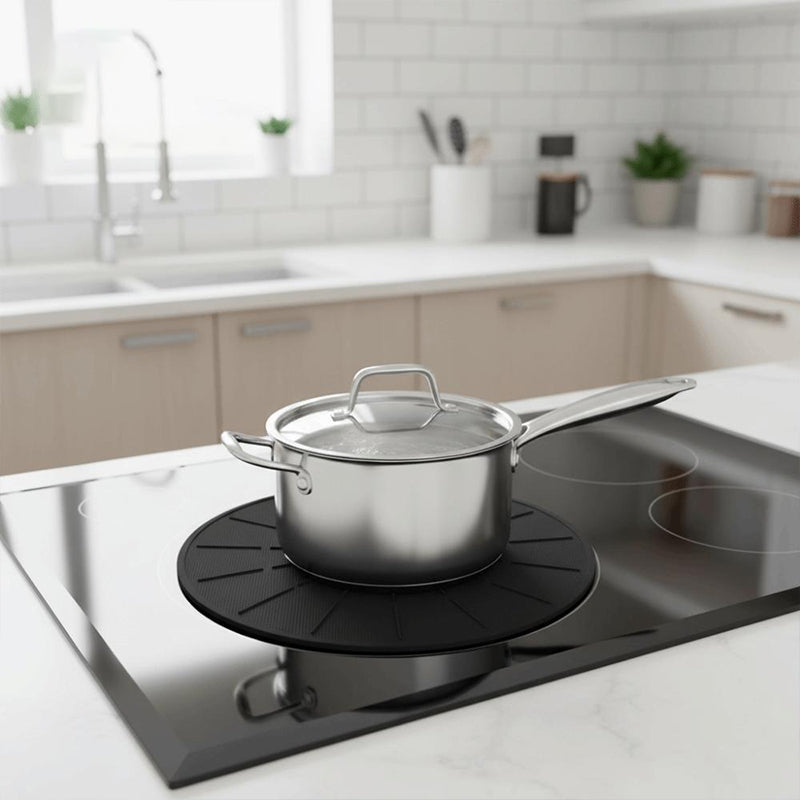 Silver pot sitting on top on cooktop mat on an induction stovetop.