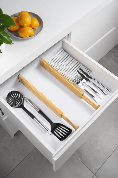 Adjustable bamboo drawer dividers positioned inside a kitchen drawer with measurement guide