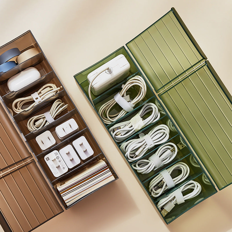 Green and brown cable organizer boxes holding charging cords, adapters, and small electronics.