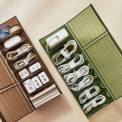Green and brown cable organizer boxes holding charging cords, adapters, and small electronics.