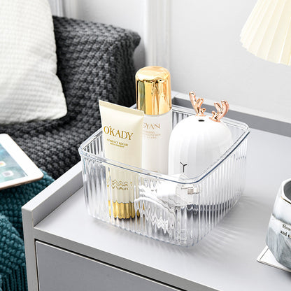 Clear square storage container with lid organizing skincare and cosmetic products on a nightstand