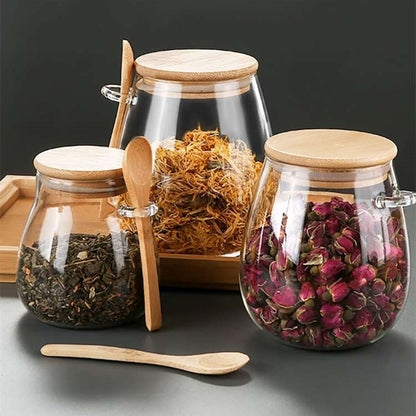 Glass spice jars with bamboo lids and spoons arranged on a wooden kitchen tray