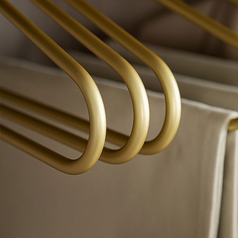 Close-up of smooth gold aluminum pants hangers holding folded trousers