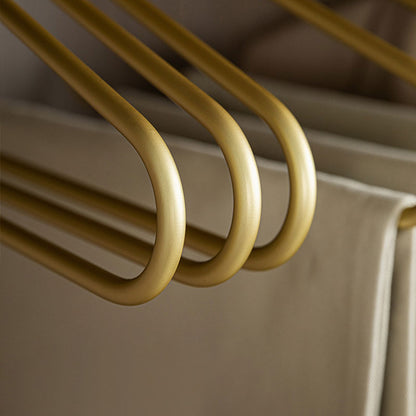 Close-up of smooth gold aluminum pants hangers holding folded trousers