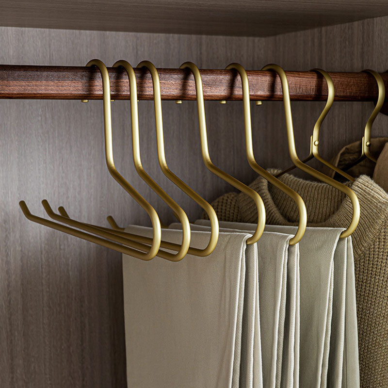 Multiple gold open-ended pants hangers organizing folded trousers in a closet
