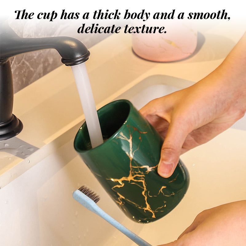 Green marble-pattern ceramic bathroom tumbler being rinsed under a faucet beside a toothbrush