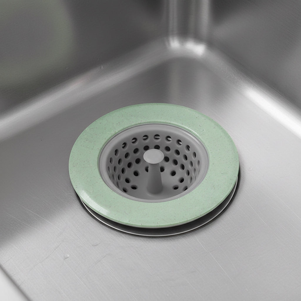 Green silicone sink drain strainer fitted over a stainless steel kitchen sink drain.