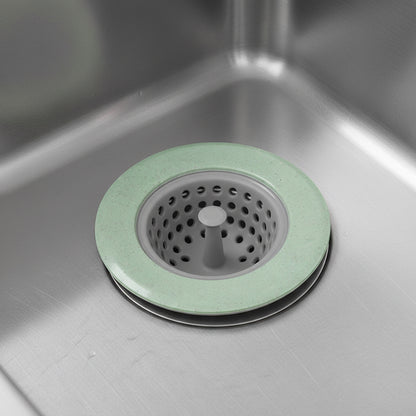 Green silicone sink drain strainer fitted over a stainless steel kitchen sink drain.