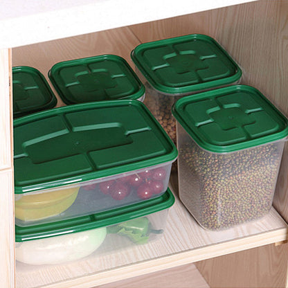 Green-lid stackable food storage containers organizing grains and fruit inside a kitchen cabinet.