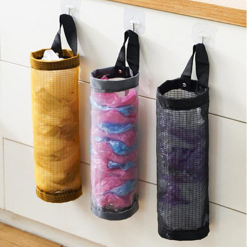 Yellow, gray, and black hanging mesh holders filled with reusable plastic bags on a kitchen wall.