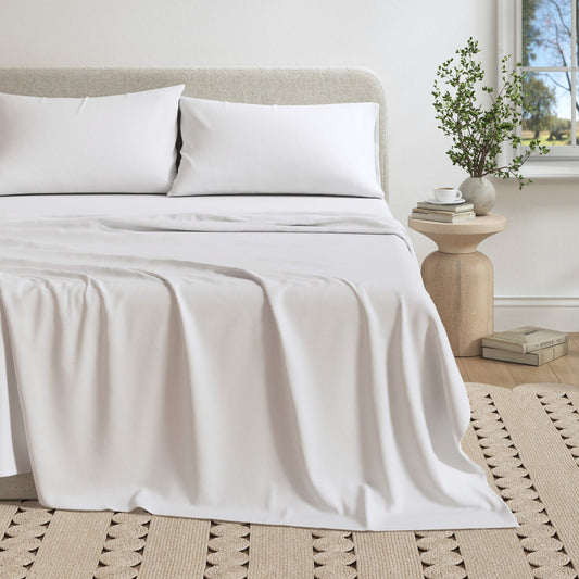 Neatly made bed with white bedding in a bedroom setting.