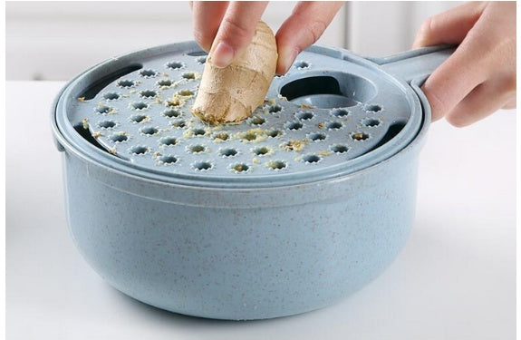 Hand grating fresh ginger with the grater attachment on a blue 8-in-1 mandoline slicer