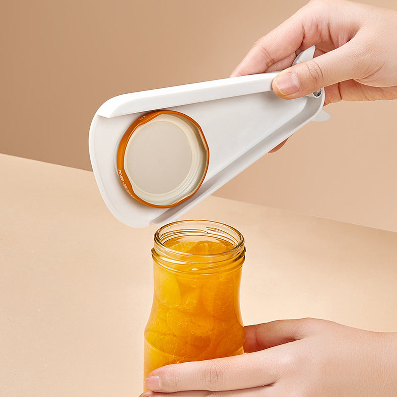 White manual opener lifting the metal lid from a glass food jar