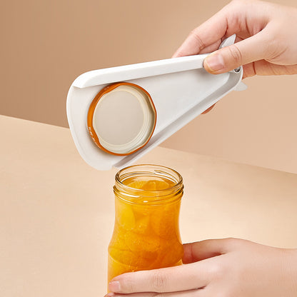 White manual opener lifting the metal lid from a glass food jar