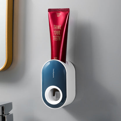 Ocean-blue and white wall-mounted toothpaste dispenser holding a red toothpaste tube.