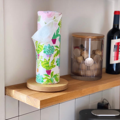 Reusable flannel paper towels with a colorful plant print rolled on a wooden holder in a kitchen