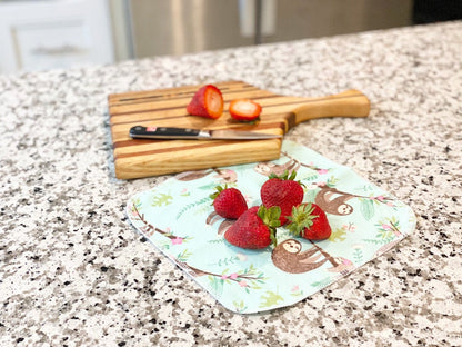 Reusable flannel paper towel with a sloth print holding fresh strawberries on a kitchen countertop