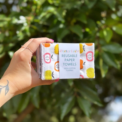 Pack of reusable cotton flannel paper towels with a colorful apple print held outdoors