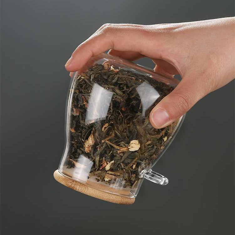 Hand holding a glass spice jar upside down to demonstrate the secure bamboo lid