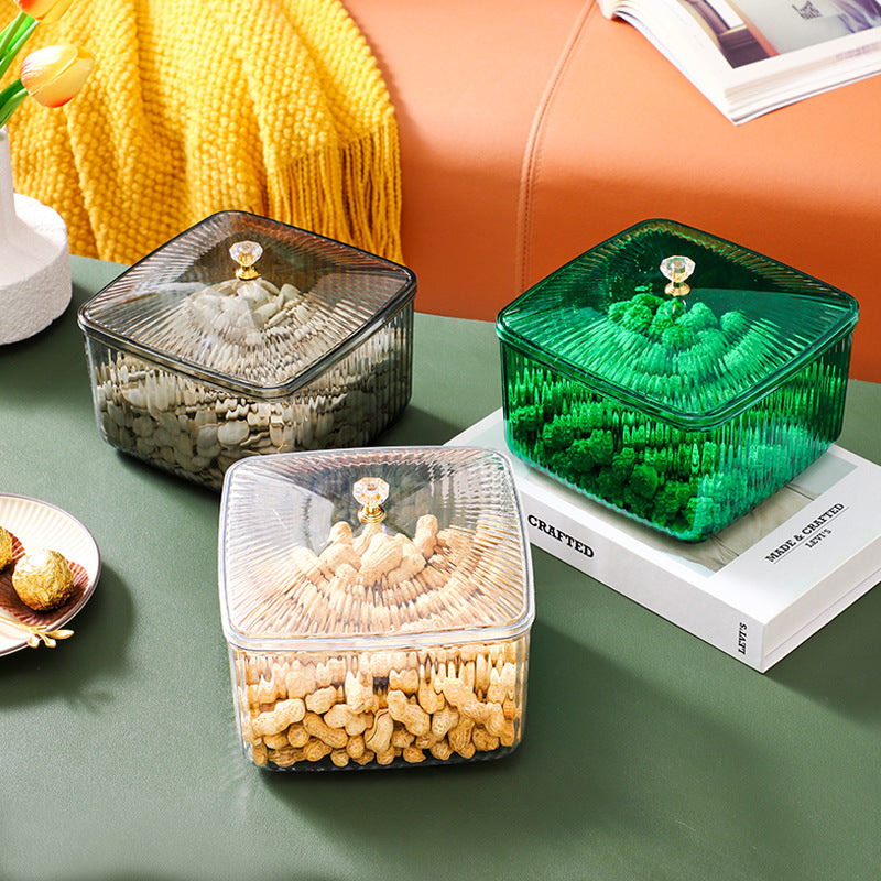 Transparent, gray, and green square storage containers with lids holding snacks