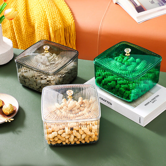 Transparent, gray, and green square storage containers with lids holding snacks