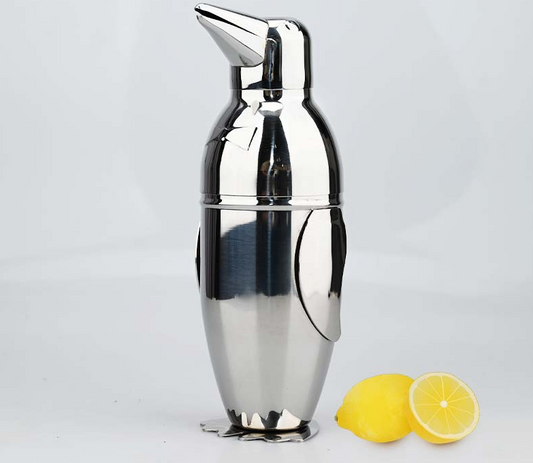 Stainless steel penguin cocktail shaker beside lemon halves