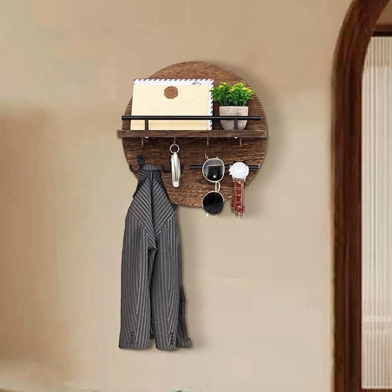 Vintage brown round entryway shelf displaying mail and a plant with hooks holding keys, accessories, and a coat